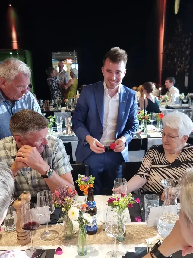 Michael Fischbacher zeigt an einem gedeckten Tisch ein Kunststück, die Gäste schauen zu